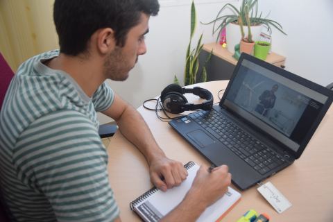 Un joven viendo en un portátil un vídeo docente de la UPCT.